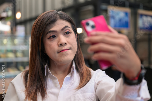 Obraz na plátne Southeast Asian Transgender Businesswoman Taking Selfie using Smartphone with Co