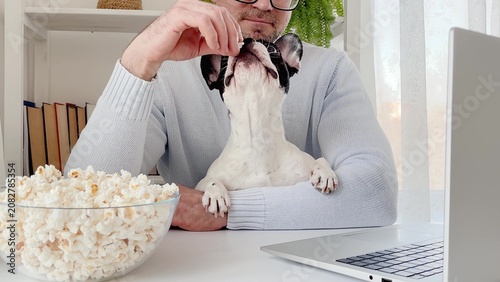Man watches a movie on a laptop with his dog