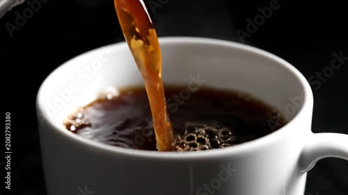 Hot Black Coffee Pouring from Teapot into White Ceramic Cup with Steam