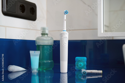 Bild auf Leinwand A set of electric toothbrush, dental floss, and mouthwash on the bathroom sink