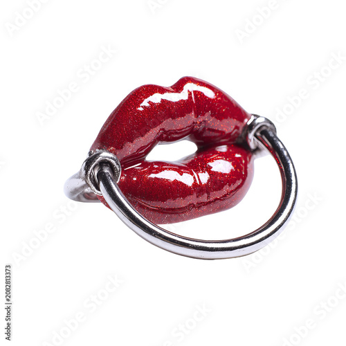 Close-up of a glossy, red, lips-shaped object pierced with a silver ring, isolated on black