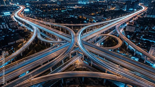 Dynamic aerial perspective of curving highway ramps with blue light trails.