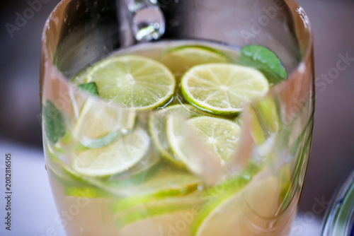 Foto A glass pitcher filled with water, slices of green lime, and vibrant mint leaves, creating a fresh and invigorating beverage