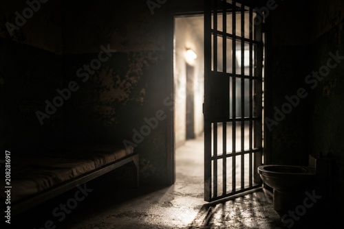 Open prison cell door with light streaming into the dark interior.
