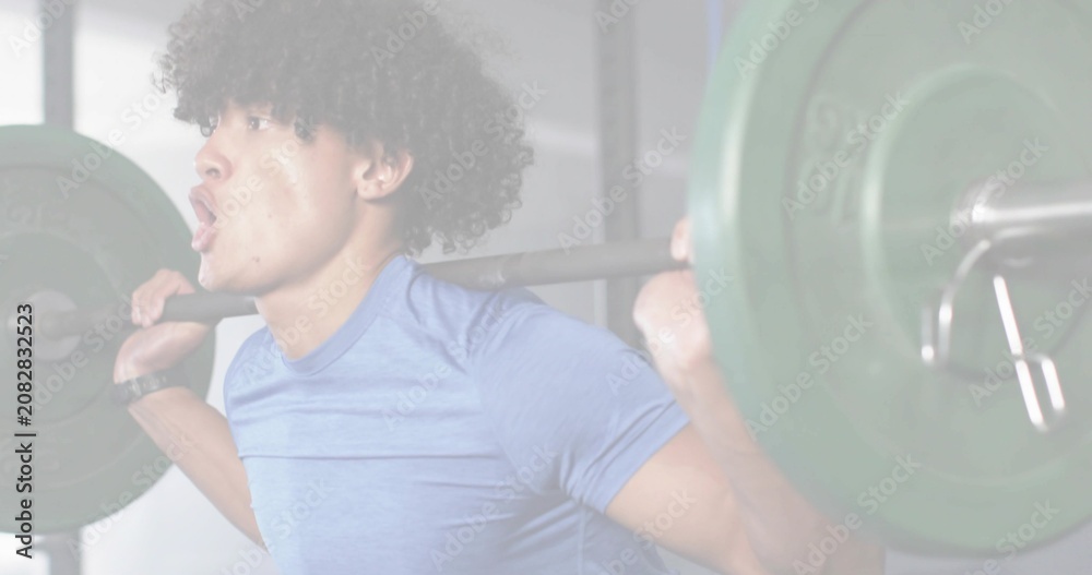 Obraz premium Man bracing core and inhaling, initiating back squat for fitness with barbell, green plates, rack