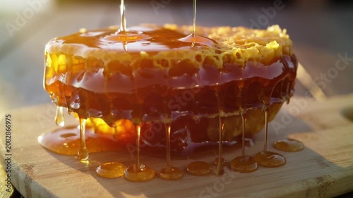 Pouring sticky sweet honey over a fresh honeycomb