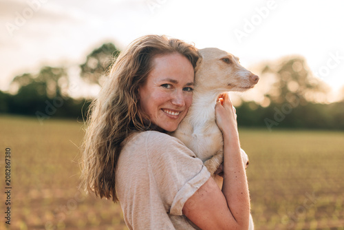 Woman hugging dog in golden hour field