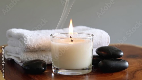 Relaxing spa setting with hot stones, white towel, and lit candle