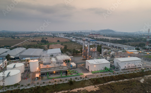 Obraz na plátně Industrial Complex at Dusk: An aerial view captures a sprawling industrial complex at dusk, with its various buildings, storage tanks, and infrastructure illuminated against the fading light