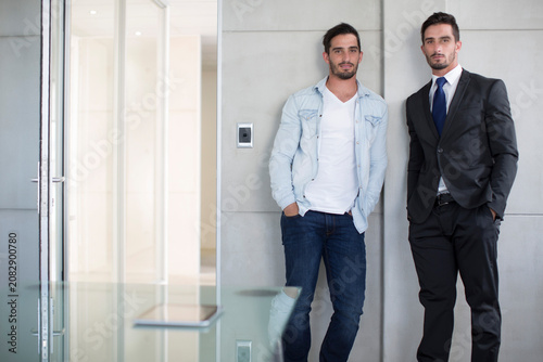 Casually and formally dressed twin males in office