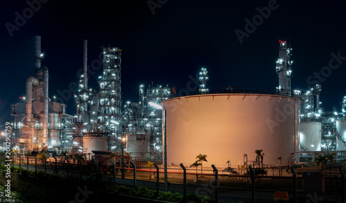 Obraz na plátně Industrial Nightscape: A sprawling oil refinery complex is illuminated against the night sky, showcasing the intricate network of pipes, towers, and storage tanks under the glow of artificial lights