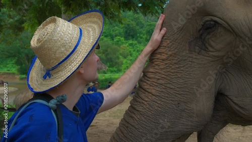 man tourist gently touching elephant in ethical wildlife sanctuary with compassion and respect, Human wildlife connection through compassionate ecotourism, elephant conservation and nature travel 4k