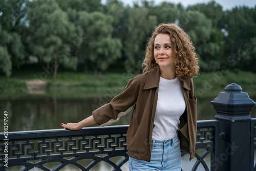 Portrait of a beautiful woman standing on the river embankment.