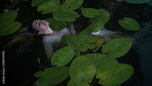 Obraz na plátne Mystical Slavic mermaid floating in deep lake water among green water lilies, pa