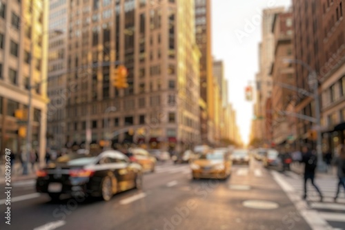 Blurred urban street scene with traffic and pedestrians in busy downtown.
