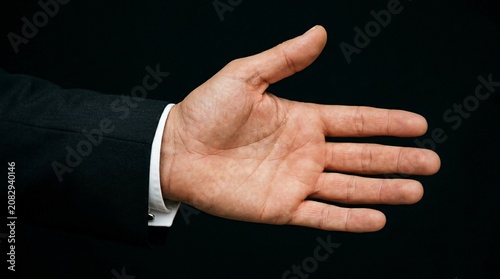 Professional businessman hand reaching for handshake, male hand in black suit jacket and white shirt cuff, corporate greeting and partnership concept