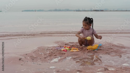 happy preschool child girl playing sand toy on the sea beach in Pattaya, Thailand