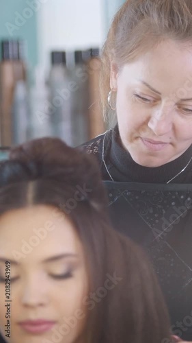 Young brunette in a beauty salon, makeup artist doing makeup, the hairdresser makes styling