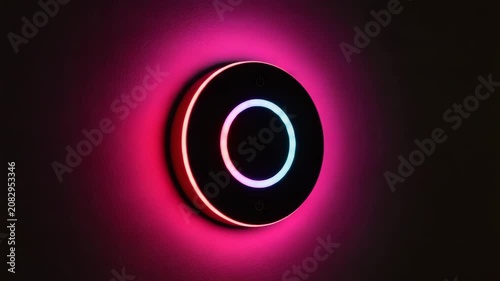 Smart light switch with colorful LED ring on dark wall  