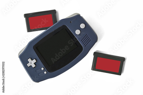 Bild auf Leinwand Top view flat lay of a classic dark blue portable handheld video game console with cartridge on PNG Di-Cut background