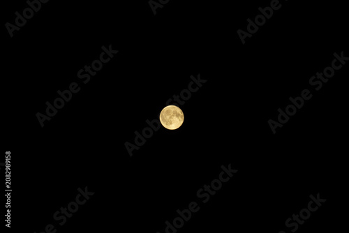 Small full moon near center on black sky with wide copy space