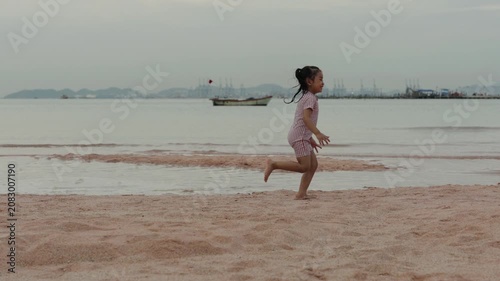 slow motion of happy preschool child girl running on the sea beach in Pattaya, Thailand