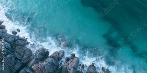 Fotografie Powerful Ocean Waves Crashing on Rocky Coastline with Sea Foam and Spray Under B