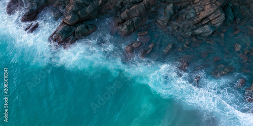 Картината върху платно Powerful Waterfall Flowing into Ocean Waves with Blue Sea Foam, Dynamic Coastal