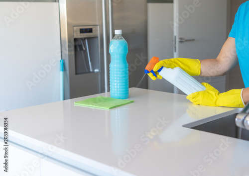 Cuadro en lienzo Person cleaning kitchen counter with spray detergent and gloves