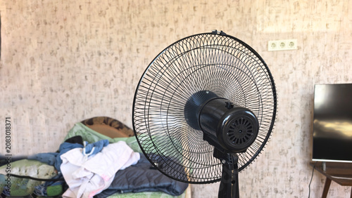 Fan spins in a room as the air circulates over surfaces and creates movement during a warm afternoon in summer