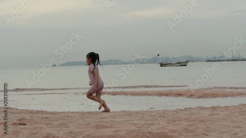 slow motion of happy preschool child girl running on the sea beach in Pattaya, Thailand