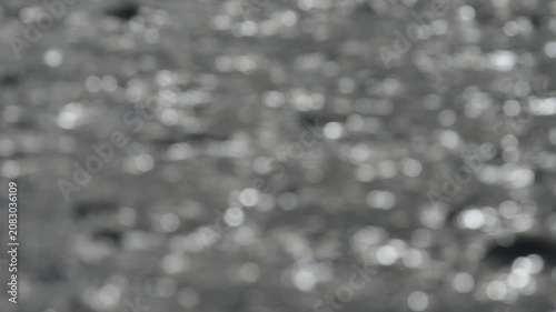 Blurred background with bright golden sun flares on rippling water surface.