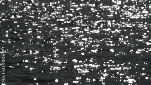 Blurred background with bright golden sun flares on rippling water surface.