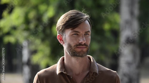 Handsome bearded man looking around and then turning to face camera.