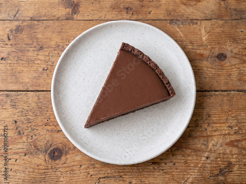 木製テーブルの上の皿にのったシンプルなチョコレートタルトのカット