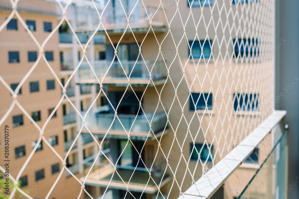 Fototapeta premium A safety net is installed on a balcony to prevent falls in a high-rise residential building in an urban setting