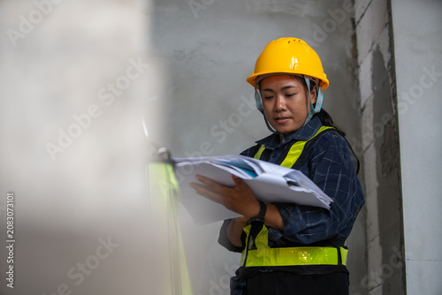 Female construction worker reviewing project plans on job site with safety gear and attention to detail
