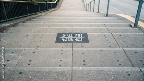 Inspirational message on a staircase promoting small steps to success in a community urban setting with a motivational tone