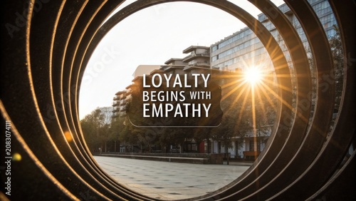 Inspirational urban scene showing the sunlight shining through a circular structure with a motivational quote on empathy and loyalty.