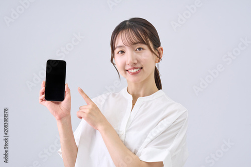 Young Japanese Woman Showing Smartphone Screen, Studio Portrait