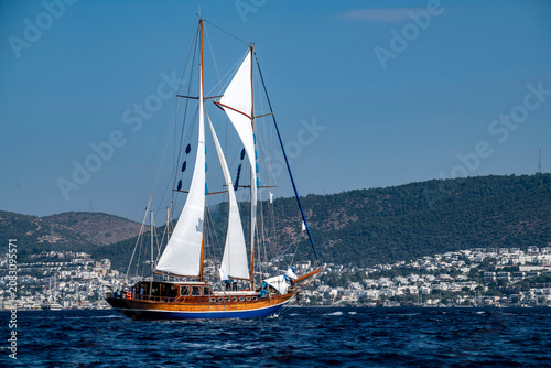 Luxury wooden sailing yacht cruising on the deep blue sea water, elegant classic sailboat navigating during a scenic summer vacation cruise travel, premium Mediterranean maritime lifestyle concept