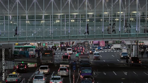 Twilight in Tokyo : Commuters Walk along a Pedestrian Skywalk Spanning a Busy Street in Front of Shibuya Station, Bustling with Neon Lights and Headlights Shining on the City | Shibuya, Tokyo, Japan