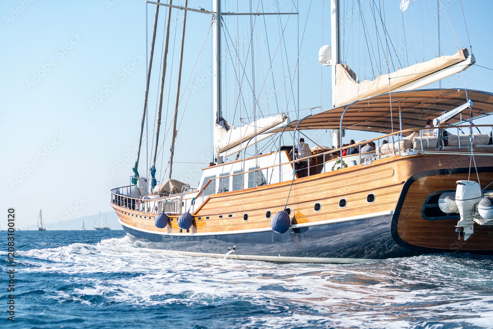Obraz premium Luxury wooden sailing yacht cruising on the deep blue sea water, elegant classic sailboat navigating during a scenic summer vacation cruise travel, premium Mediterranean maritime lifestyle concept