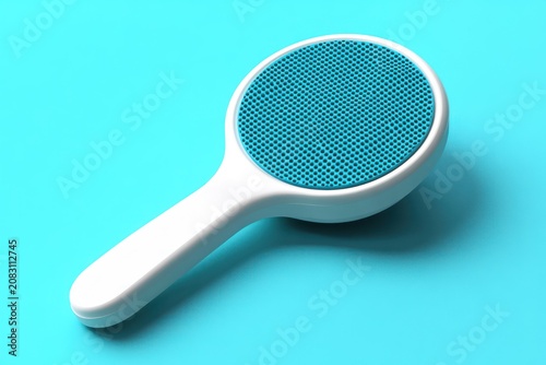 A white-handled, round, blue-bristled brush on a blue background