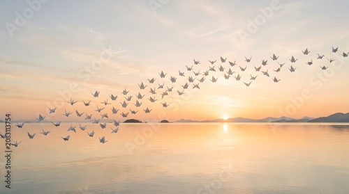 A surreal and peaceful digital art composition depicting a large flock of white origami paper cranes flying gracefully in a sweeping curve across a calm ocean at sunset
