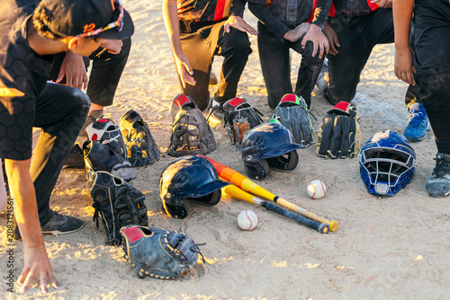 Wall Mural Youth baseball players gathered in a huddle, their helmets, bats, gloves, and ca