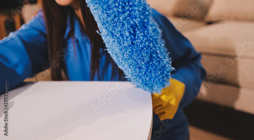 Person cleaning the room, cleaning staff is using cloth and spraying disinfectant to wipe the tables in the company office room. Cleaning staff. Maintaining cleanliness in the organization.
