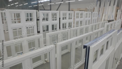 Rows of white wood frame windows displayed inside a modern manufacturing factory with bright industrial lighting, organized production area, and spacious interior