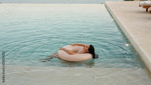 Serene vacation scene of a woman floating in a spacious oceanview pool