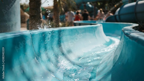 Vacation atmosphere with water streams and people in the background at a water park slide